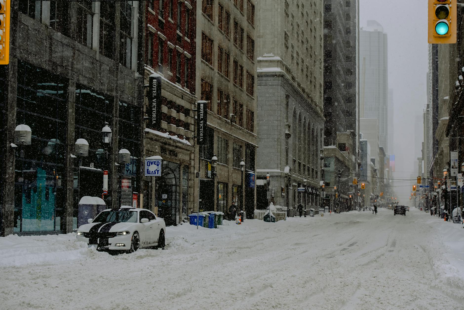 Winter city street scene with snow covering roads and buildings, capturing urban life in cold weather.